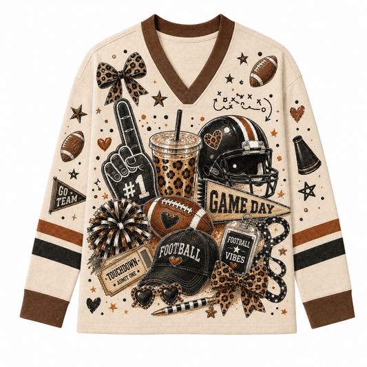 Front view of the cream long sleeve jersey displaying a crowded game day graphic collage including a foam finger, leopard iced coffee cup, football helmet, and leopard bows.