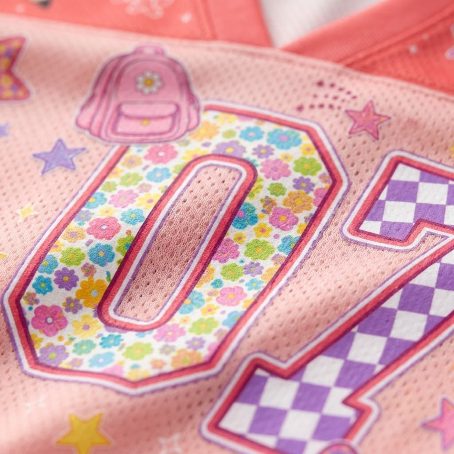 Macro close-up shot of the graphic print on mesh fabric, focusing on the high-definition textures of the floral pattern number 01 and pink checkerboard star details.