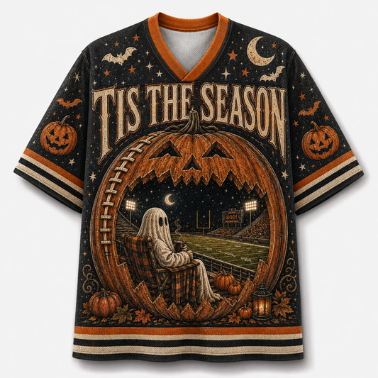 A Halloween-themed short-sleeve V-neck jersey with a detailed graphic print. The design features a large jack-o'-lantern with a ghost sitting in the stands at a football field, surrounded by 'TIS THE SEASON' text, pumpkins, bats, and stars on a dark background.