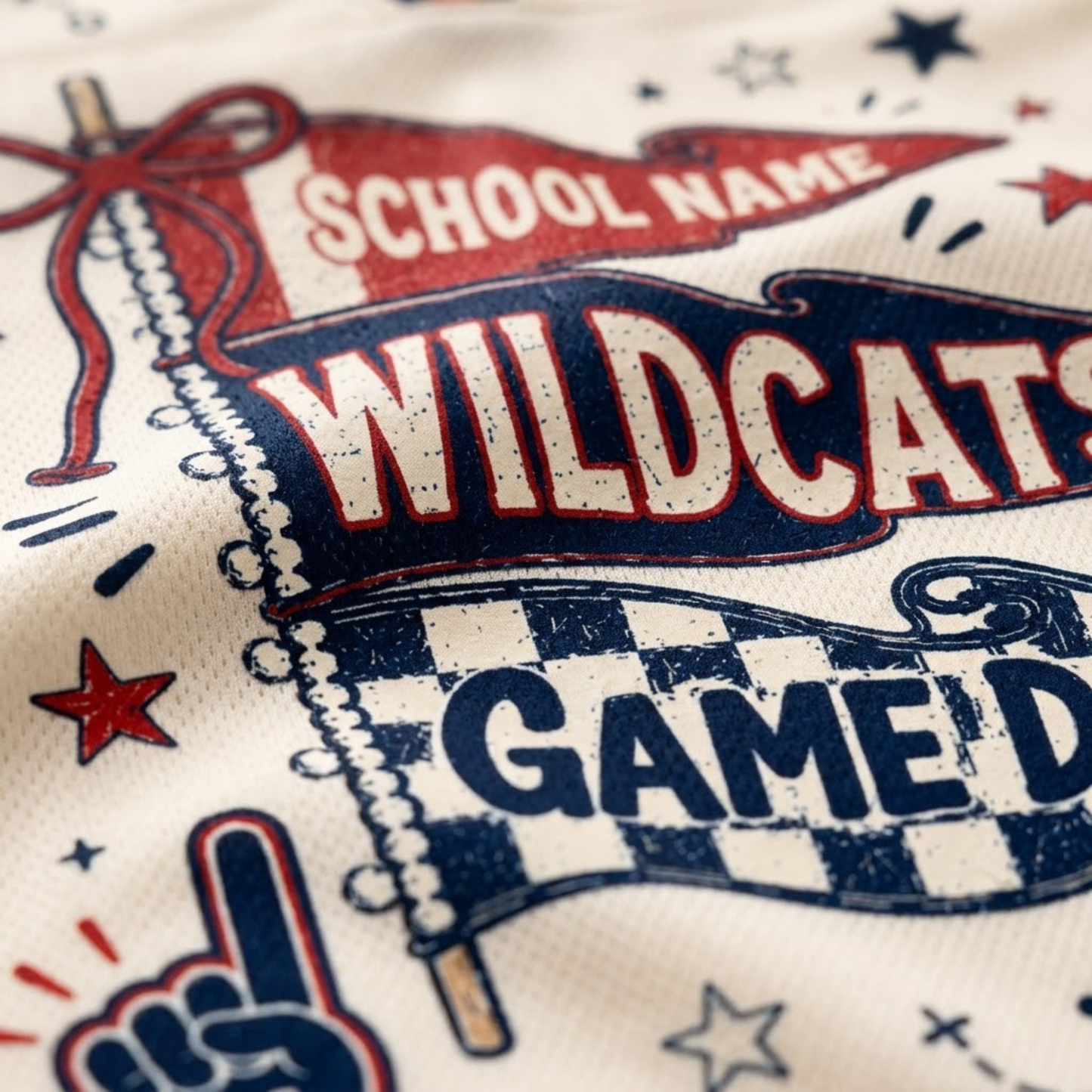 Close-up of a white athletic jersey fabric printed with a red, white, and navy blue 'Wildcats Game Day' graphic, including a pennant, stars, and a foam finger.