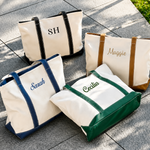 Four personalized tote bags with names embroidered on them, placed on a stone surface.
