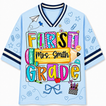 Front view of the light blue ChaoticClub Doodle Back to School Teacher Mesh Jersey, featuring colorful patchwork "FIRST GRADE" text, a large yellow pencil graphic with customizable "Mrs. Smith" name, and small school doodles.