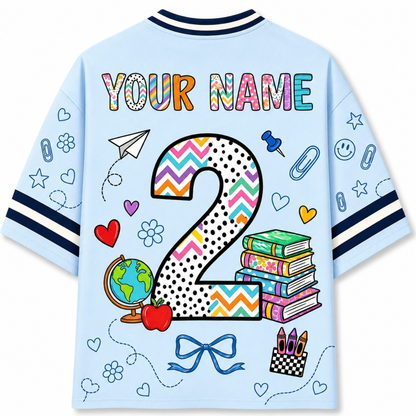 Front and back views of the light blue ChaoticClub Doodle Back to School Teacher Mesh Jersey, showcasing the "KINDERGARTEN" pencil graphic on the front and custom name personalization with a large patterned number 2 on the back.