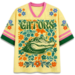 Front view of the white ChaoticClub Floral School Spirit Personalized Mesh Jersey, featuring a large yellow pastel Gators mascot head surrounded by a symmetrical folk-art floral border in orange and blue, with row of stars below the v-neck collar.