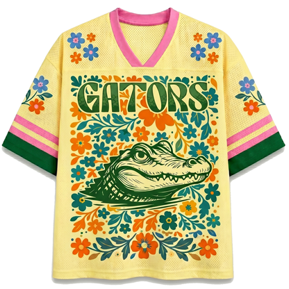Front view of the white ChaoticClub Floral School Spirit Personalized Mesh Jersey, featuring a large yellow pastel Gators mascot head surrounded by a symmetrical folk-art floral border in orange and blue, with row of stars below the v-neck collar.