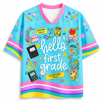 Front view of the light blue ChaoticClub Hello Team Level Teacher Mesh Jersey, featuring bold white "hello FIRST GRADE" text surrounded by school supplies like a backpack, crayons, notebooks, an apple on books, a globe, and butterflies.