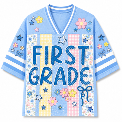 Front view of the light blue ChaoticClub Preppy School Grade Floral Pearl Striped Mesh Jersey, featuring bold dotted "FIRST GRADE" text on a background of pastel yellow gingham, pink gingham, and floral stripes, decorated with cute flower and star graphics.