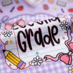 Pencil case with 'First Grade' text on a purple background with school-themed decorations.
