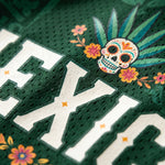 Close-up of a sports jersey with a colorful skull and floral design on a green background.