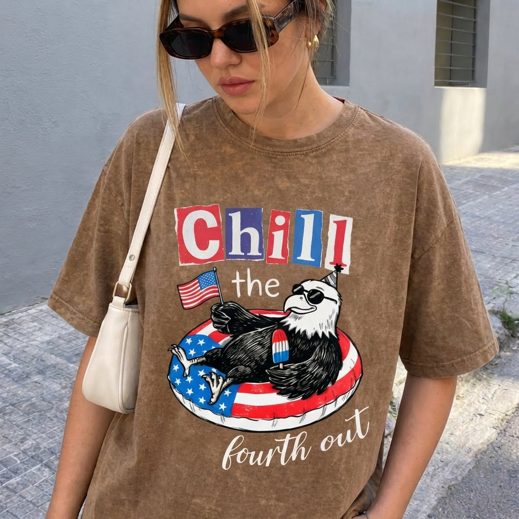 ChaoticClub Chill The Fourth Out Eagle Washed T-Shirt, vintage oversized graphic tee featuring a cool bald eagle in sunglasses and a party hat lounging in a patriotic pool float with a popsicle and an American flag with funny text on premium washed cotton fabric