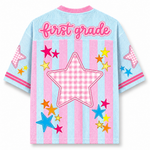 Children's shirt with 'first grade' text and colorful stars on a blue and pink striped background