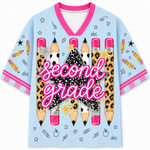 A light blue V-neck t-shirt with a 'second grade' school-themed graphic print featuring pencils, stars, apples, and checkmarks on a white background.