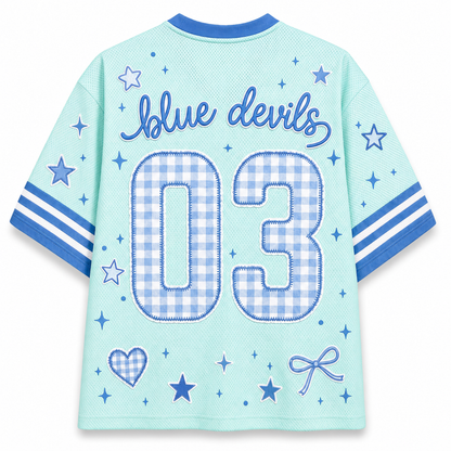 The back of a light blue mesh short-sleeve jersey with blue trim, featuring 'blue devils' in script and the number '03' in a blue-and-white gingham pattern. The sleeves have blue and white stripes, and the back is decorated with blue stars, hearts, and bows.