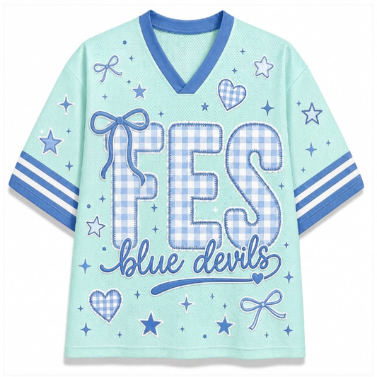 A light mint green short-sleeve V-neck t-shirt with blue trim, featuring a 'FES blue devils' graphic on the front with gingham patterned letters and blue star, heart, and bow motifs.
