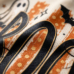 Detailed close up of Chaotic Club ghost illustration peeking out from the black BOO lettering on distressed orange polka dot background stripes.