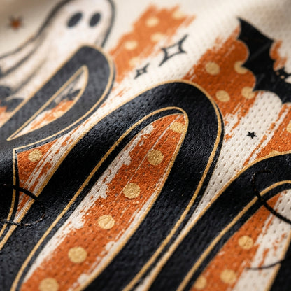 Detailed close up of Chaotic Club ghost illustration peeking out from the black BOO lettering on distressed orange polka dot background stripes.