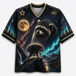 A short-sleeve V-neck t-shirt featuring a detailed graphic print of two raccoons over a mountain landscape with a moon, aurora, and waterfall. The shirt has a black base with gold trim on the collar and cuffs, and gold and teal details in the print.