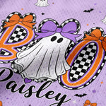 Close-up of a purple fabric featuring a Halloween-themed personalized design with the name 'Paisley' in black script, a white ghost with a purple bow, and large orange-and-black checkered letters spelling 'BOO'.