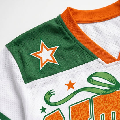 Close-up of a white mesh sports jersey with green and orange accents, featuring a green shoulder patch with an orange-outlined white star and part of a green-and-orange graphic on the front.