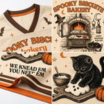 A Halloween-themed sports jersey shown in a four-panel collage. The cream-colored mesh jersey features brown and orange trim, bat silhouettes, and spooky graphics including a bakery oven, a black cat kneading a ghost, pumpkins, and the text 'Spooky Biscuits Bakery' and 'We Knead Em You Need Em'.