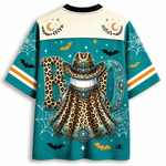 A short-sleeve graphic T-shirt shown from the back, featuring a Halloween-themed design with a leopard-print cowboy hat and cape, large 'BOO' lettering, bats, spiders, moons, and stars on a teal background.