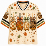 Front view of the cream varsity jersey displaying four caramel-dipped apples styled with plaid, maple leaf, and leopard patterns with coquette ribbon bows.