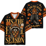 A black V-neck short-sleeve t-shirt shown from both front and back, featuring a fall raccoon graphic wearing a knit hat and scarf, with autumn leaves, pumpkins, stars, and the text 'TIS THE FALL SEASON' in gold.