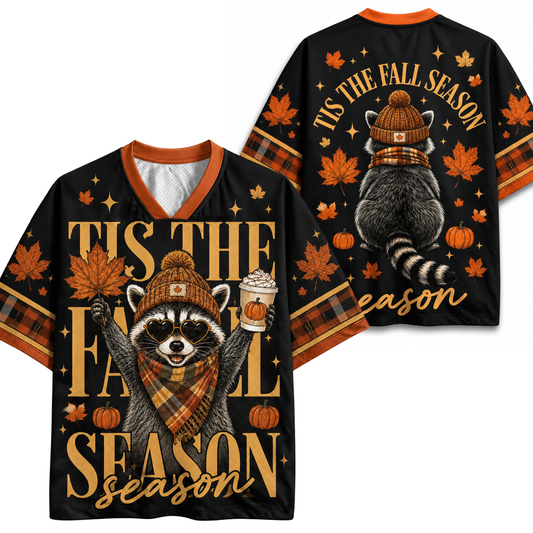 A black V-neck short-sleeve t-shirt shown from both front and back, featuring a fall raccoon graphic wearing a knit hat and scarf, with autumn leaves, pumpkins, stars, and the text 'TIS THE FALL SEASON' in gold.