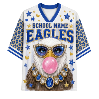A white V-neck athletic jersey with blue and gold graphics, featuring a bald eagle wearing blue and gold jewelry and blowing a pink bubblegum bubble. The jersey has 'SCHOOL NAME EAGLES' printed across the chest, blue leopard-print sleeves, and blue and gold star details.
