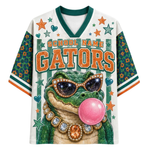 A custom white and green V-neck athletic jersey featuring a cartoon alligator wearing sunglasses and a pink bubblegum bubble. The jersey has 'SCHOOL NAME GATORS' printed on the front, with green patterned sleeves and green, orange, and white striped trim.