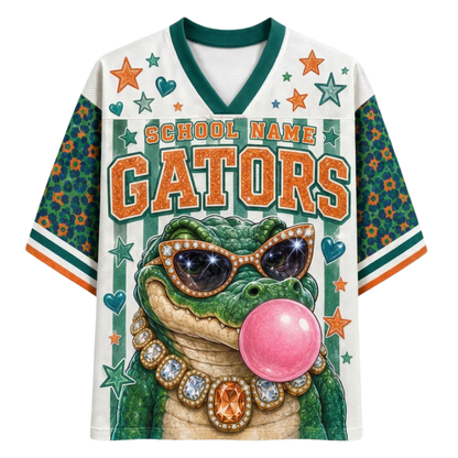 A custom white and green V-neck athletic jersey featuring a cartoon alligator wearing sunglasses and a pink bubblegum bubble. The jersey has 'SCHOOL NAME GATORS' printed on the front, with green patterned sleeves and green, orange, and white striped trim.
