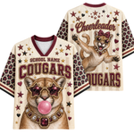 Front and back views of a women's V-neck cheerleader cougar jersey. The cream-colored shirt features a cougar graphic wearing star-shaped sunglasses and bubblegum bubble, with 'SCHOOL NAME COUGARS' and 'Cheerleader' text, plus leopard-print sleeves and star heart patterns.