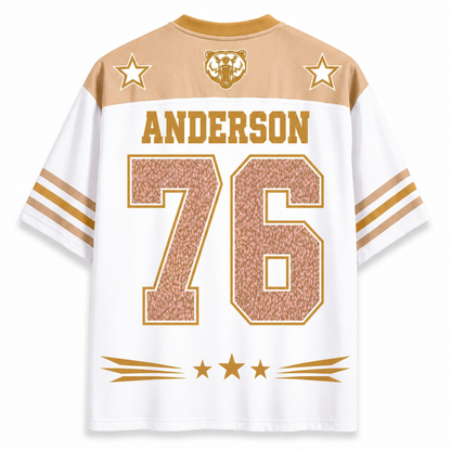 White short-sleeve athletic jersey with tan shoulder panels, gold lettering reading ANDERSON, large textured gold number 76 on the back, two gold stars, and a bear head crest at the collar.