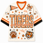 A custom short-sleeve V-neck athletic jersey in cream with orange and black accents. The jersey features a large orange and black gingham block-letter 'TIGERS' print on the front, a smaller orange and black gingham bow graphic on the right chest, a small orange and black gingham pennant flag on the left chest, and a tiger face graphic on the lower right.