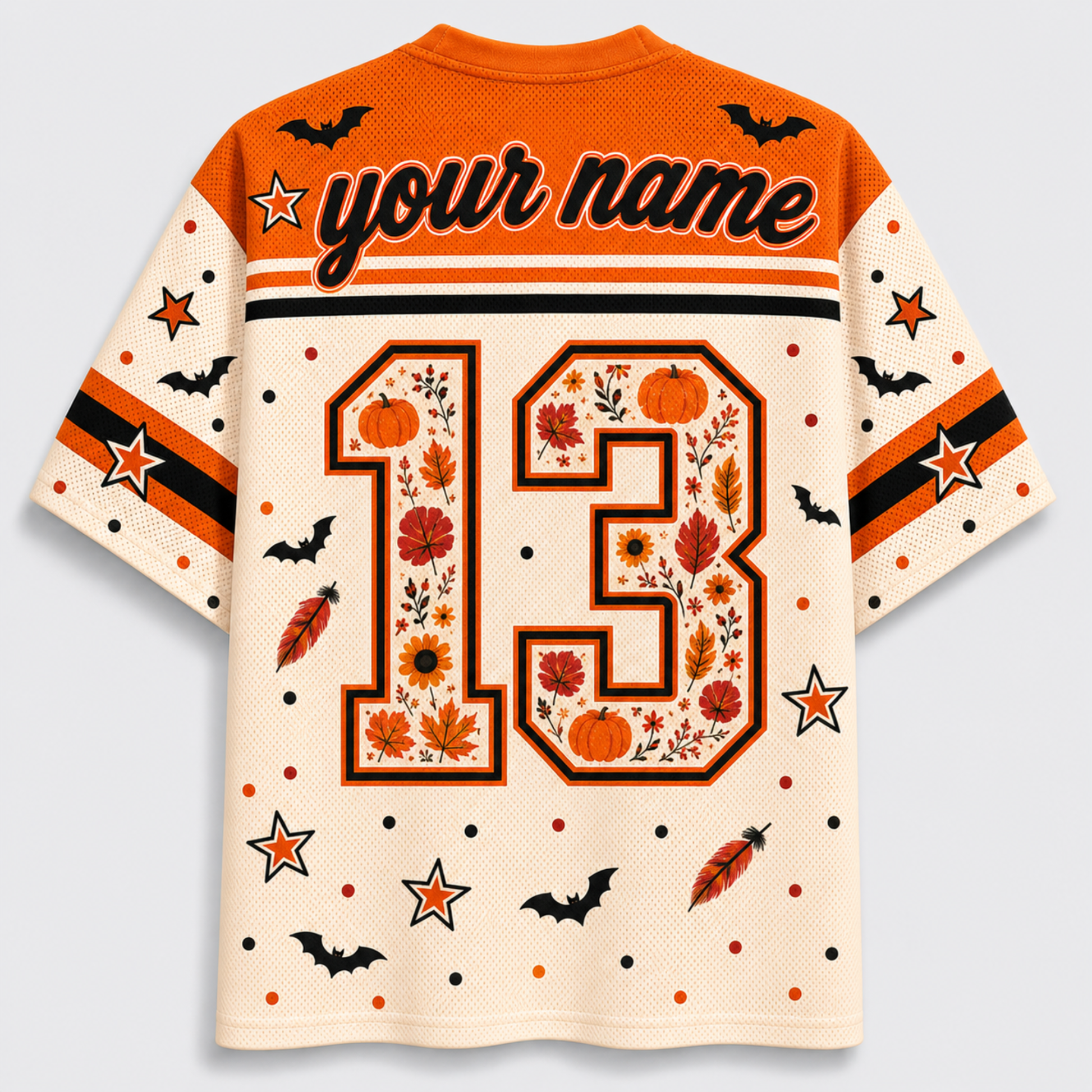 A short-sleeve mesh jersey-style shirt shown from the back on a light gray background. The shirt is cream with orange and black graphics, including the text 'your name', a large number 13 filled with autumn leaves and pumpkins, stars, bats, and feather motifs.