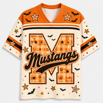 A short-sleeve football-style jersey with a Halloween theme, featuring an orange and cream color palette. The front displays a large letter 'M' with a plaid pattern, the word 'Mustangs' in black script, and various printed motifs including bats, stars, and horseshoes.