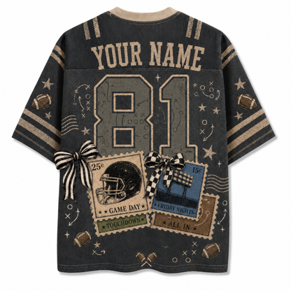 A dark gray short-sleeve t-shirt with a custom sports theme, featuring 'YOUR NAME' and the number '81' on the back. The design includes football motifs, stars, doodles, and two ticket graphics tied with black-and-white striped bows.