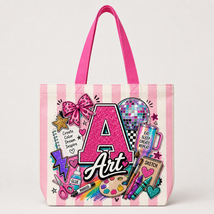 A canvas tote bag with pink and white vertical stripes, featuring a colorful 'Art' themed graphic print with a glittery pink letter 'A', a disco ball, paint palette, and sketchbook illustrations.