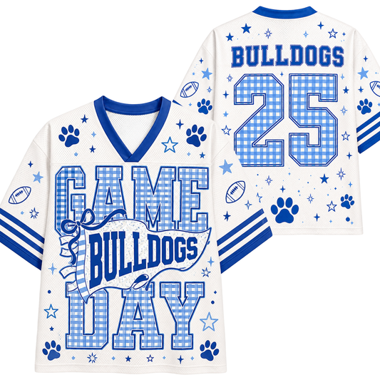 White and blue football-style jersey shown from the front and back, with 'BULLDOGS', 'GAME DAY', and the number '25' printed in blue gingham and solid blue on a white mesh background. The design includes paw prints, stars, footballs, and stripes.