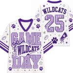 White and purple football-style jersey shown from the front and back, with 'GAME WILDCATS DAY' on the front, 'WILDCATS 25' on the back, paw prints, stars, footballs, and a megaphone graphic.