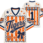 Custom tiger-themed football jersey shown from both front and back. The jersey has an off-white base with navy blue and orange graphics, including 'Tigers' script, a large number 1, paw print, bow, stars, stripes, and tiger head illustrations.