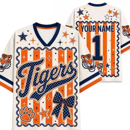 Custom tiger-themed football jersey shown from both front and back. The jersey has an off-white base with navy blue and orange graphics, including 'Tigers' script, a large number 1, paw print, bow, stars, stripes, and tiger head illustrations.