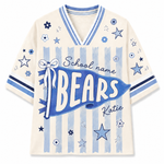 A cream-colored short-sleeve V-neck t-shirt with a blue and light blue sports-themed graphic. The design features a large blue banner reading 'BEARS' with 'School name' and 'Katie' written above and below, alongside blue stars, flowers, and vertical stripes.