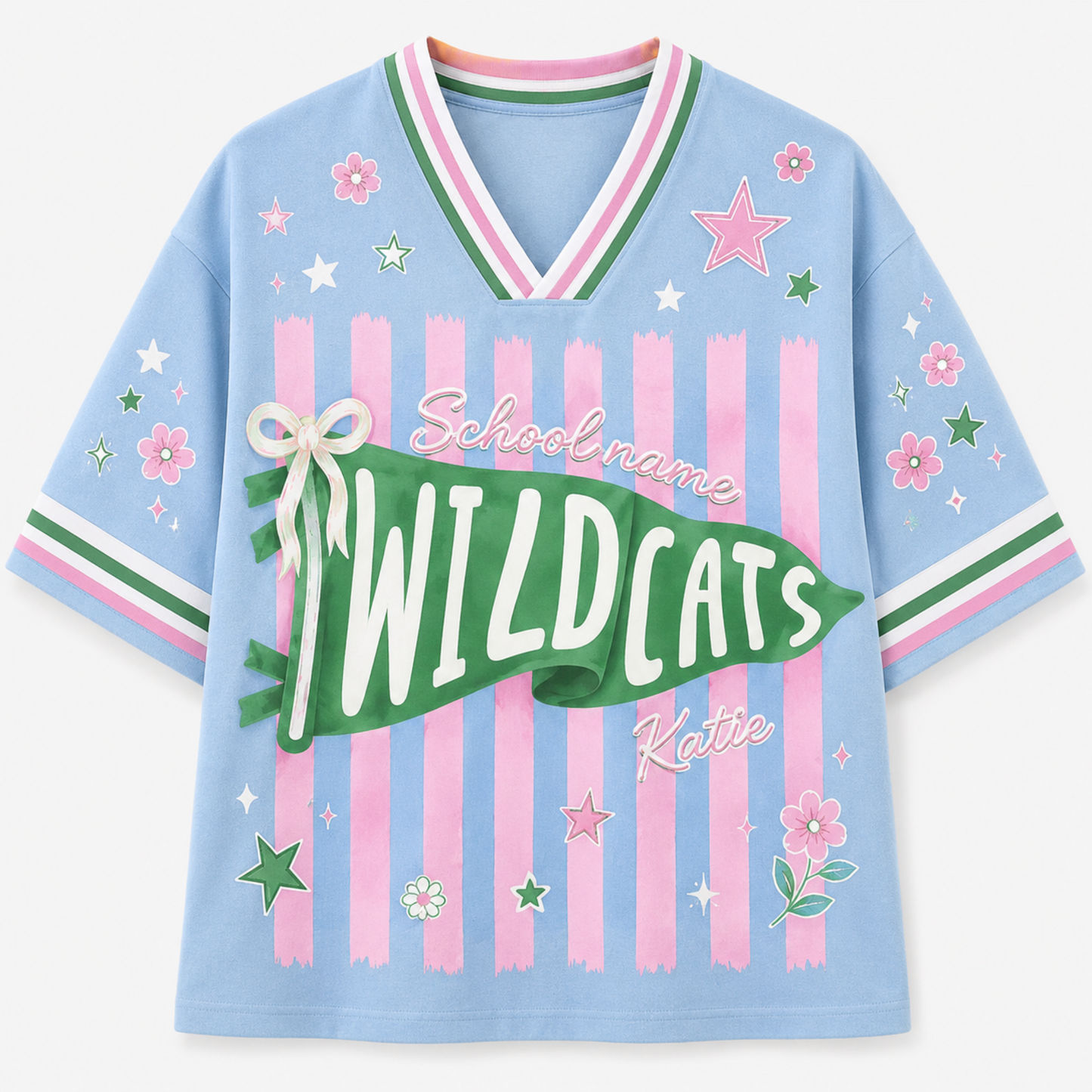 A light blue short-sleeve V-neck t-shirt with pink and green striped details, decorated with pink stars, flowers, and a green banner reading 'WILDCATS' with 'School name' and 'Katie' written on it.