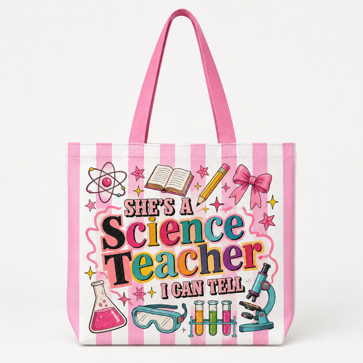 A pink and white striped tote bag featuring a colorful graphic that reads 'She's a Science Teacher I Can Tell' surrounded by science-themed illustrations including a microscope, beaker, test tubes, and an atom symbol, shown on a clean white background.