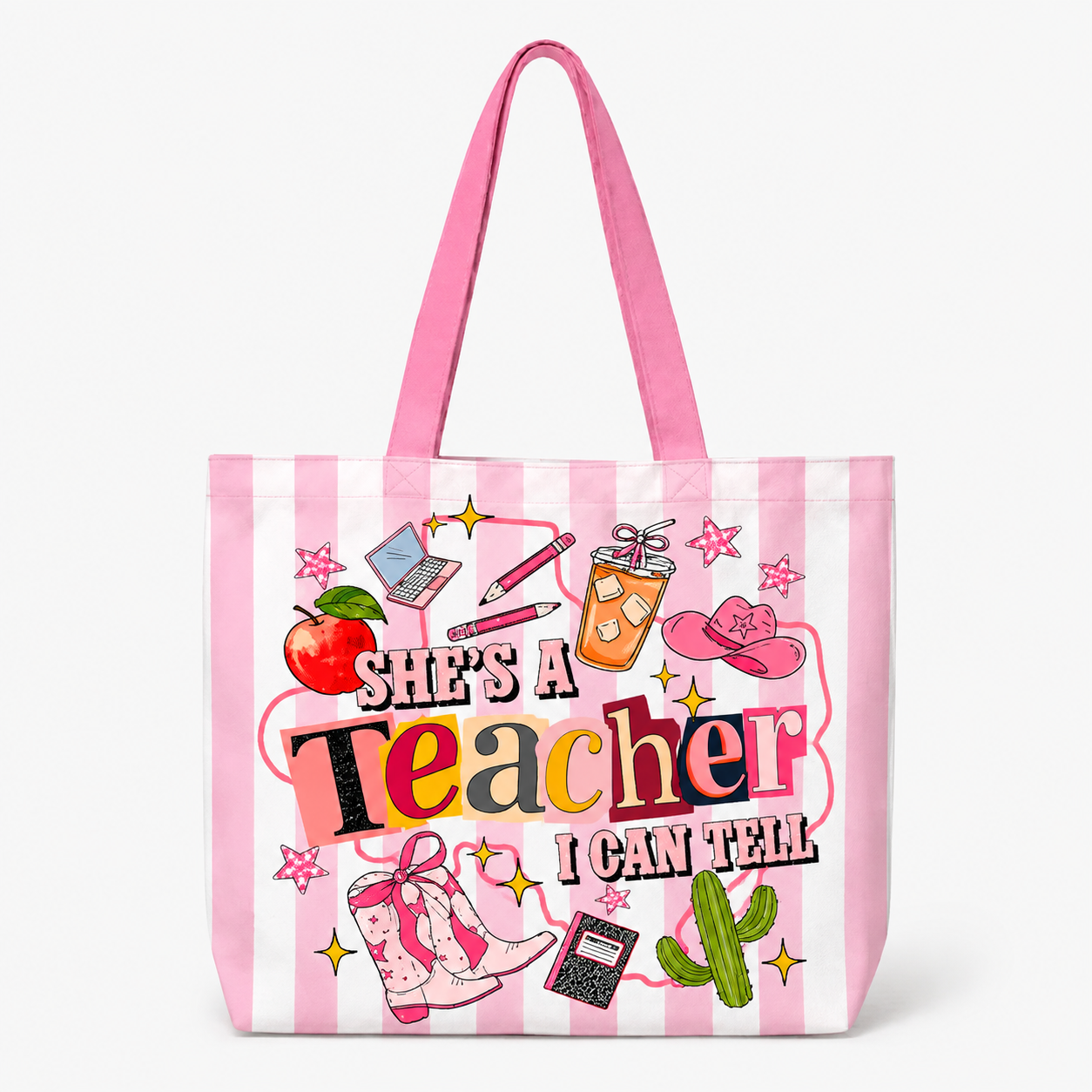 A pink and white striped tote bag with a colorful graphic that reads 'She's a Teacher I Can Tell' surrounded by school and western-themed illustrations, shown on a clean white background.