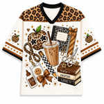 Front view of the cream varsity mesh jersey showcasing stacked school books labeled Teach Inspire Love, a leopard print apple with star glasses, and a cold brew coffee print.