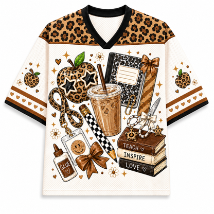 Front view of the cream varsity mesh jersey showcasing stacked school books labeled Teach Inspire Love, a leopard print apple with star glasses, and a cold brew coffee print.