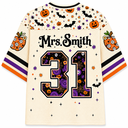 A cream-colored short-sleeve jersey with Halloween-themed graphics, including pumpkins, bats, stars, and purple swirls. The back of the jersey features the text 'Mrs.