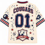 Back view of a cream-colored sports jersey featuring 'COUGARS' and '01' in navy and red, decorated with football-themed graphics including a helmet, paw prints, stars, and a 'GAME DAY' banner.
